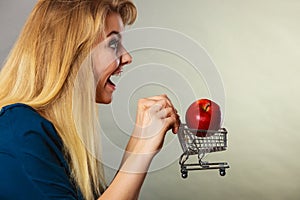 Woman holding shopping cart with apple inside