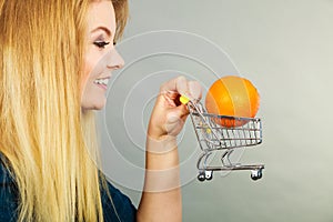 Woman holding shopping cart with orange inside