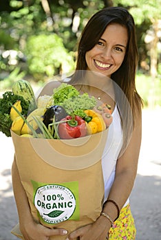 Woman holding shopping paper bag with organic or bio vegetables and fruits.