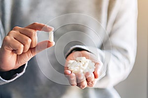 A woman holding and showing white medicine capsules in hand