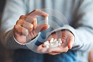 A woman holding and showing white medicine capsules in hand