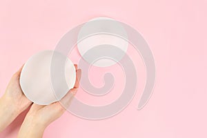 Woman holding silicone implant for breast augmentation on color background, top view with space for text.