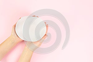 Woman holding silicone implants for breast augmentation on color background, top view with space for text