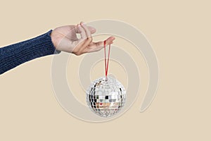 Woman holding silver christmas disco ball isolated on flesh color background