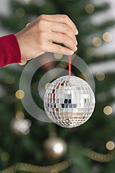 Woman holding silver christmas disco ball on christmas tree background