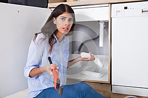 Woman Holding Sink Pipe And Monkey Wrench