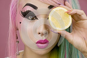 Woman holding slice of lemon in front of her eyes