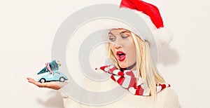 Woman holding small car with Christmas tree