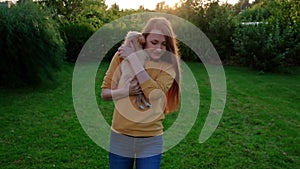 Woman holding a small cute Chihuahua puppy at sunset.