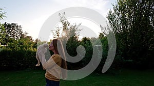 Woman holding a small cute Chihuahua puppy at sunset.