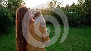 Woman holding a small cute Chihuahua puppy at sunset.