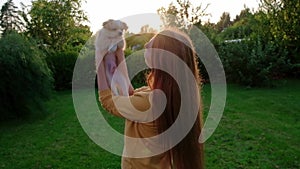 Woman holding a small cute Chihuahua puppy at sunset.