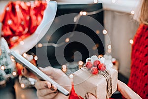 Woman holding small present box in hand and using search by laptop. Christmas Concept. Online shopping. Holiday sale