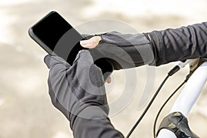 Woman holding smartphone with black screen while sitting on her bicycle
