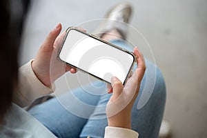 A woman holding a smartphone in a horizontal position, watching a video or playing a mobile game