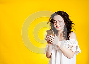 Woman holding smartphone over yellow background