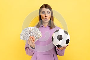 Woman holding soccer ball and fan of dollars, amazed of football championship, betting.