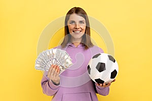 Woman holding soccer ball and fan of dollars, celebrating victory on football championship, betting.