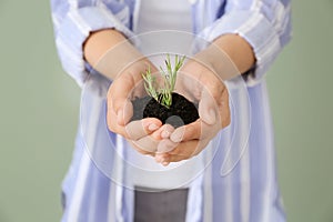 Woman holding soil with green plant in hands, closeup. Ecology concept