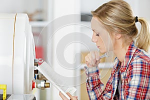 woman holding spanner and reading instructions for appliance