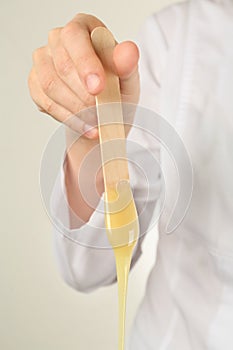 Woman holding spatula with hot depilatory wax, closeup