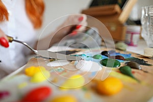 Woman holding a spatula over a palette with paints