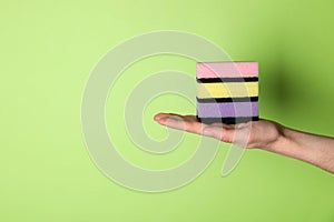 Woman holding sponges on green background, closeup. Space for text