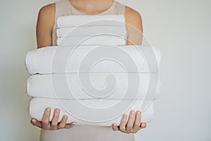 A woman is holding a stack of white towels. Concept of service i