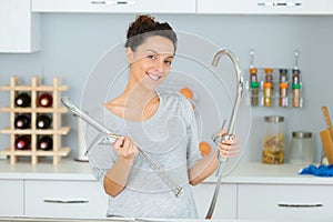 Woman holding stainless tap in kitchen