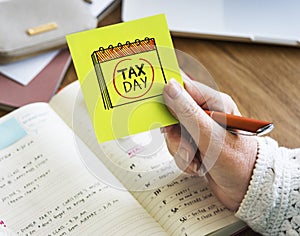 Woman holding a sticky note with tax day circled