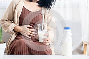 Woman holding stomachache and a glass of cow milk having gas, heartburn, feeling discomfort because of  indigestion system photo