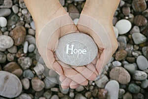 Woman holding stone with the word Hope in her palms