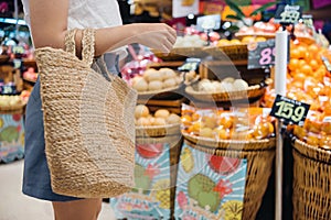 a woman holding a straw bag in a grocery supermarket, a lifestyle of sustainability and environmental conservation concept