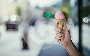 Woman is holding strawberry ice cream in her hand, beautiful summer day