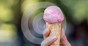 Woman is holding strawberry ice cream in her hand, beautiful summer day