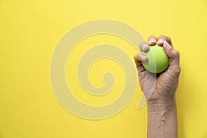 Woman holding stress ball on yellow background