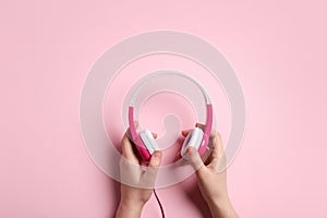Woman holding stylish headphones on color background