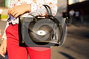 Woman holding stylish leather purse walking at the city. Closeup shot