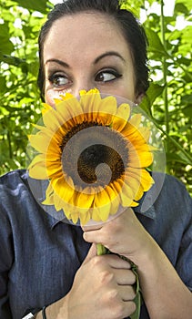 Woman holding sunflower to her face