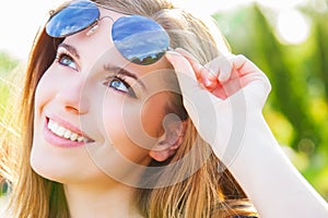 Woman holding sunglasses and smiling