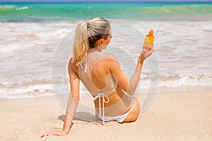 Woman holding sunscreen lotion on the beach