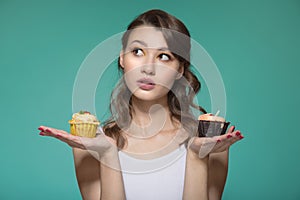 Woman holding a sweet dessert. Choose between two cakes. Turquoise background