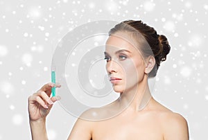 Woman holding syringe with injection over snow