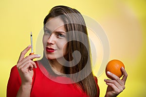 Woman holding a syringe and an orange
