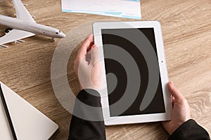 Woman holding tablet with blank screen over table. Travel agency