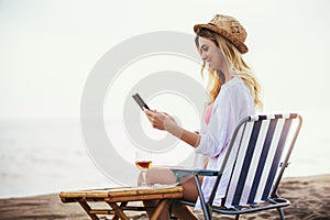 Woman holding tablet computer sitting on the beach