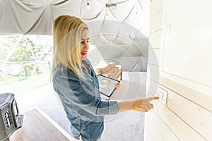 woman holding a tablet computer with system clever house on a screen on the background of the house