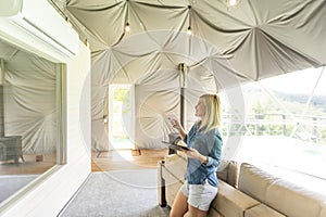 woman holding a tablet computer with system clever house on a screen on the background of the house