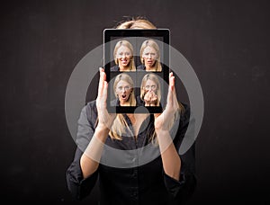 Woman holding tablet with different faces in front of her