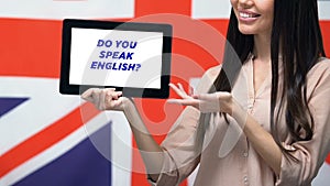 Woman holding tablet with do you speak English phrase against British flag, app
